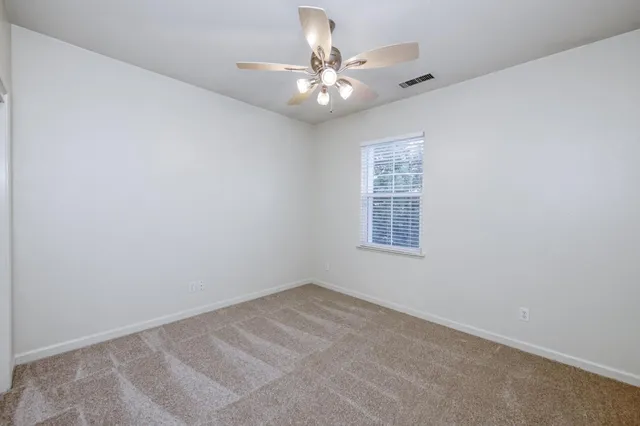 an empty room with a window and a fan