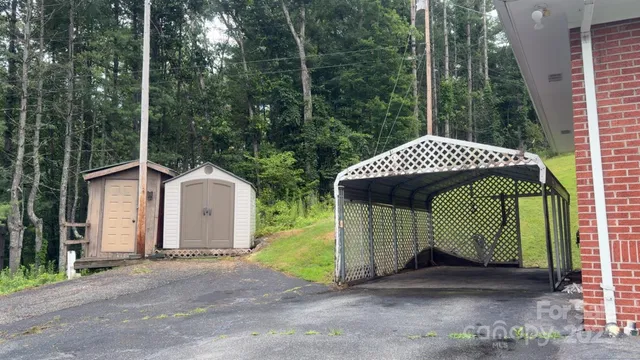 a view of a barn with a small yard and a large parking space