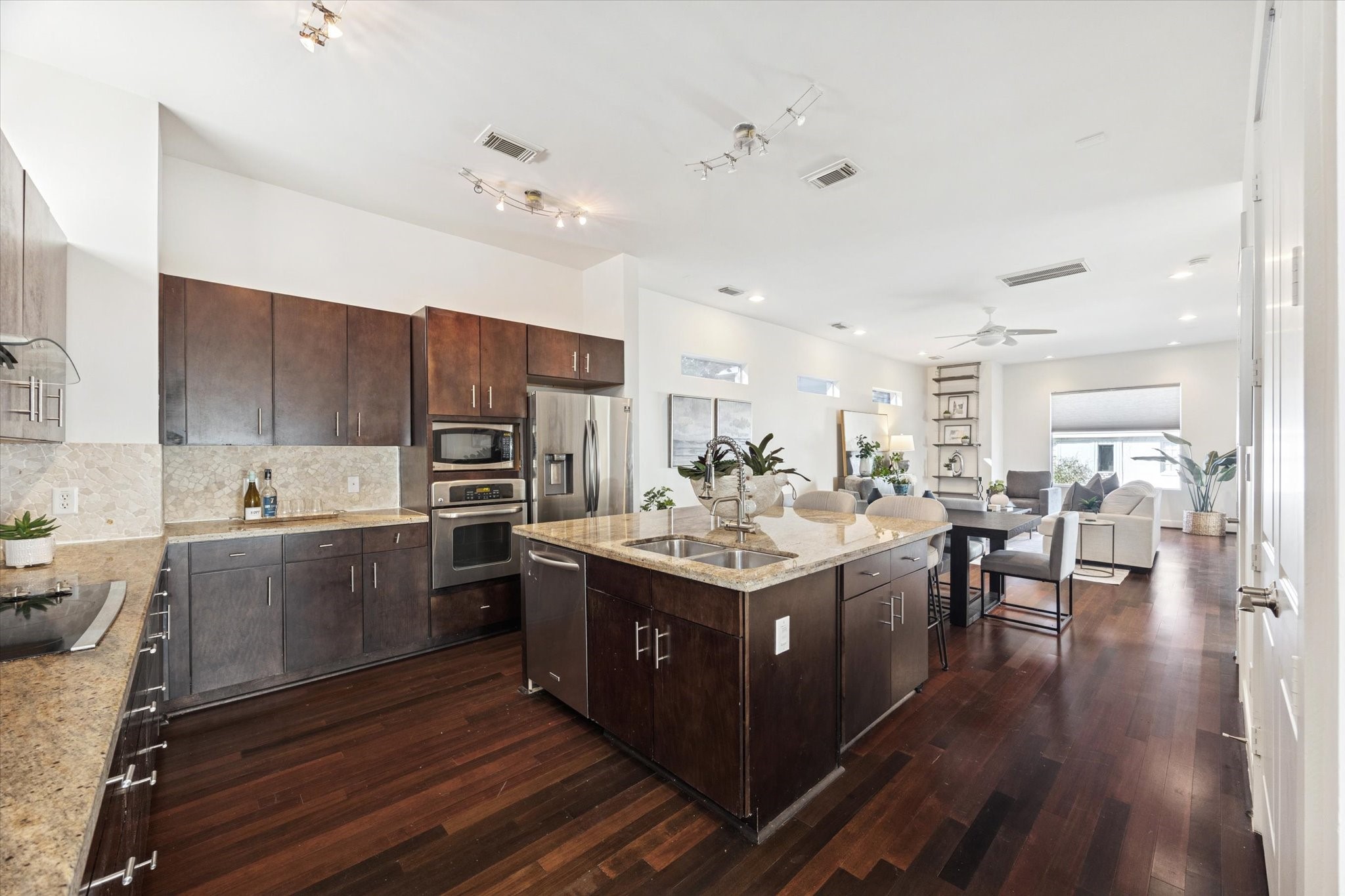1821 West Main Street, Unit A Houston, TX 77098 - Photo 4 of 12 Open-concept kitchen and living area featuring rich hardwood floors, oversized island with seating, granite countertops, stainless steel appliances, and seamless entertaining flow.