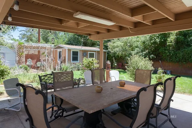a view of a patio with table and chairs under an umbrella with a small yard