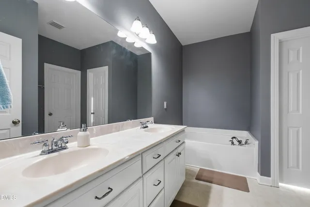 a bathroom with a tub sink and mirror