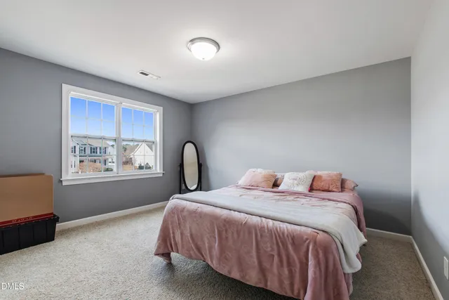 a bed sitting in a spacious bedroom next to a window
