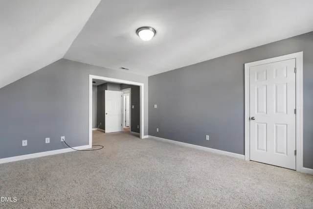 a view of an empty room with closet and a window