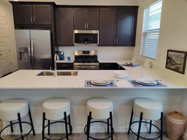 a kitchen with stainless steel appliances a sink a stove a refrigerator cabinets and dining table