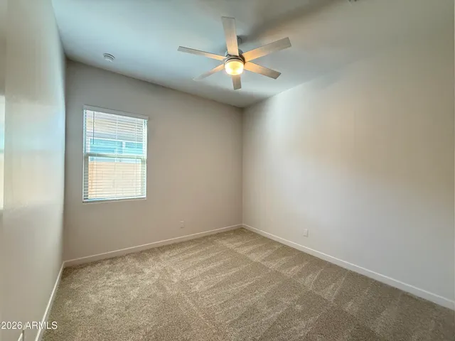 an empty room with a ceiling fan and window