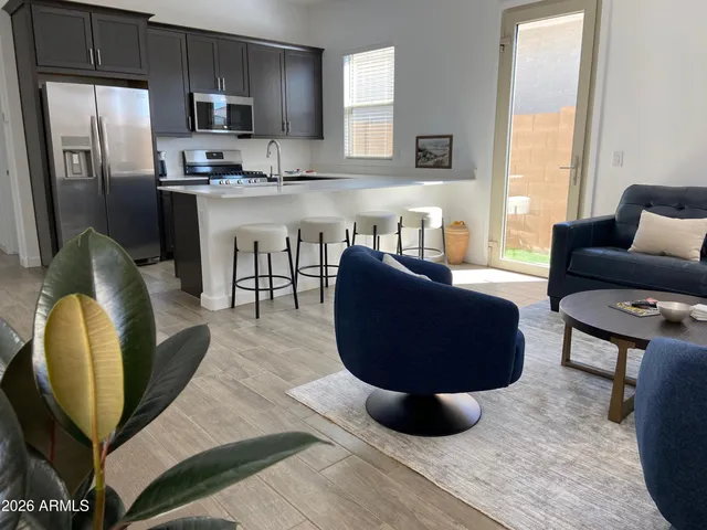 a living room with stainless steel appliances furniture a rug and a window