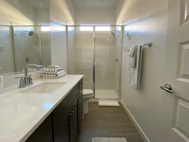 a bathroom with a double vanity sink a toilet and shower