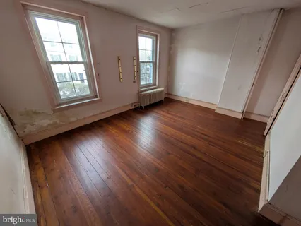 a view of an empty room with wooden floor and window