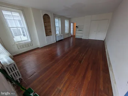 a view of an empty room with wooden floor and windows