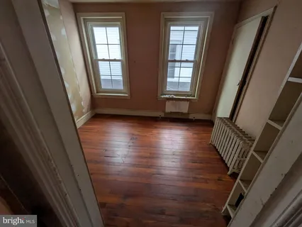 a view of an empty room with wooden floor and windows