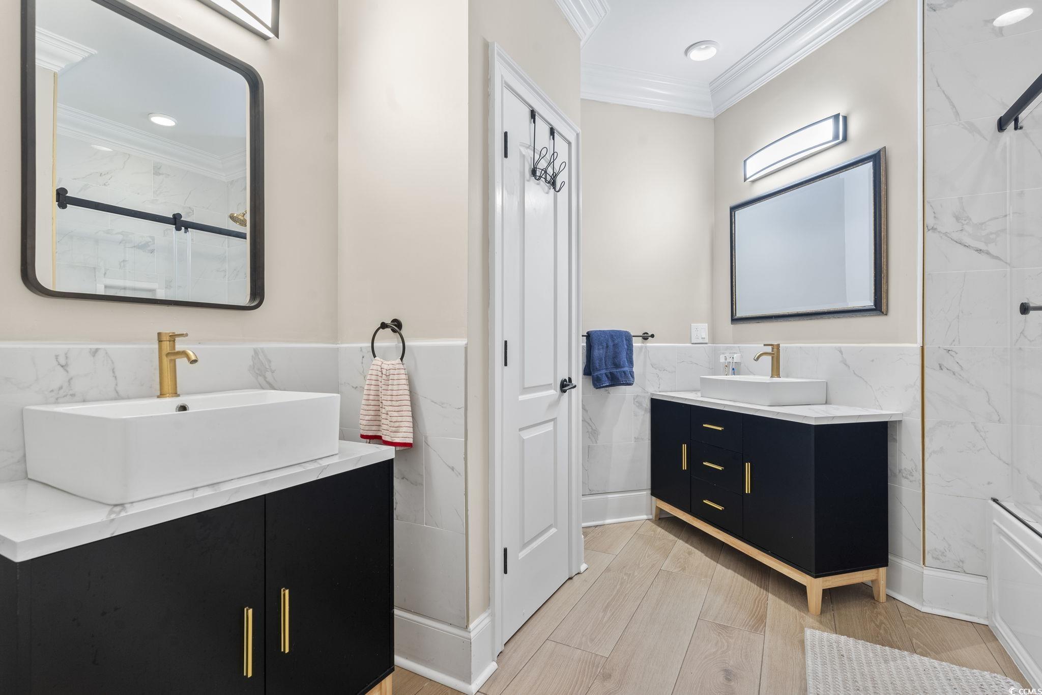 9449 Freewoods Road Myrtle Beach, SC 29588 - Photo 28 of 39 Full bath with crown molding, tile walls, two vanities, a marble finish shower, and a wainscoted wall