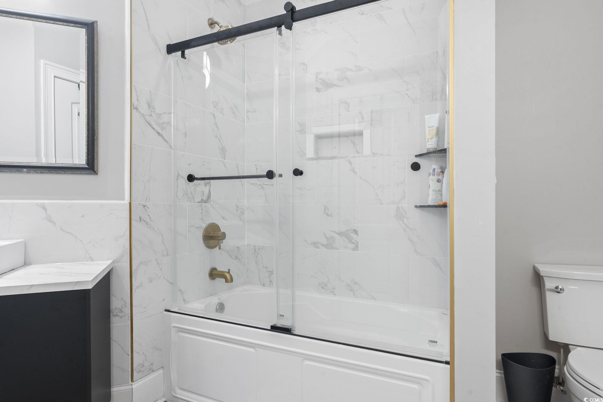 9449 Freewoods Road Myrtle Beach, SC 29588 - Photo 29 of 39 Full bathroom featuring toilet, shower / bath combination with glass door, and tile walls