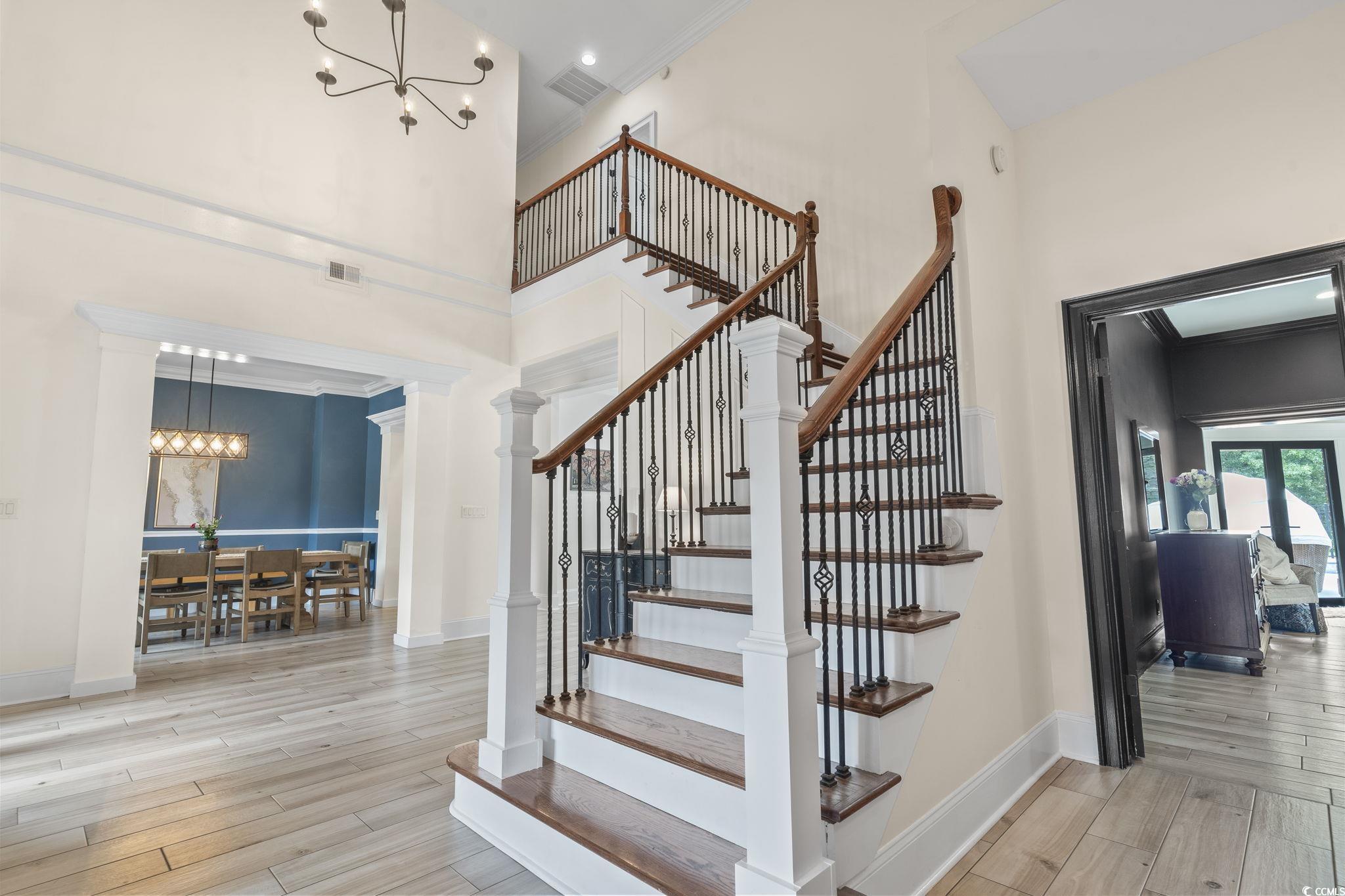 9449 Freewoods Road Myrtle Beach, SC 29588 - Photo 3 of 39 Stairs with a chandelier, a towering ceiling, baseboards, wood finished floors, and ornamental molding