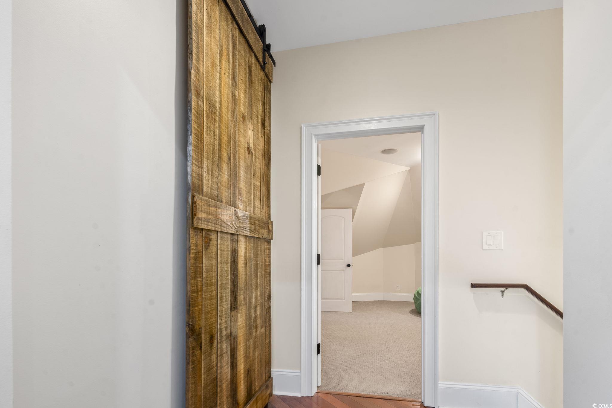 9449 Freewoods Road Myrtle Beach, SC 29588 - Photo 30 of 39 Corridor with wood finished floors, baseboards, lofted ceiling, and a barn door