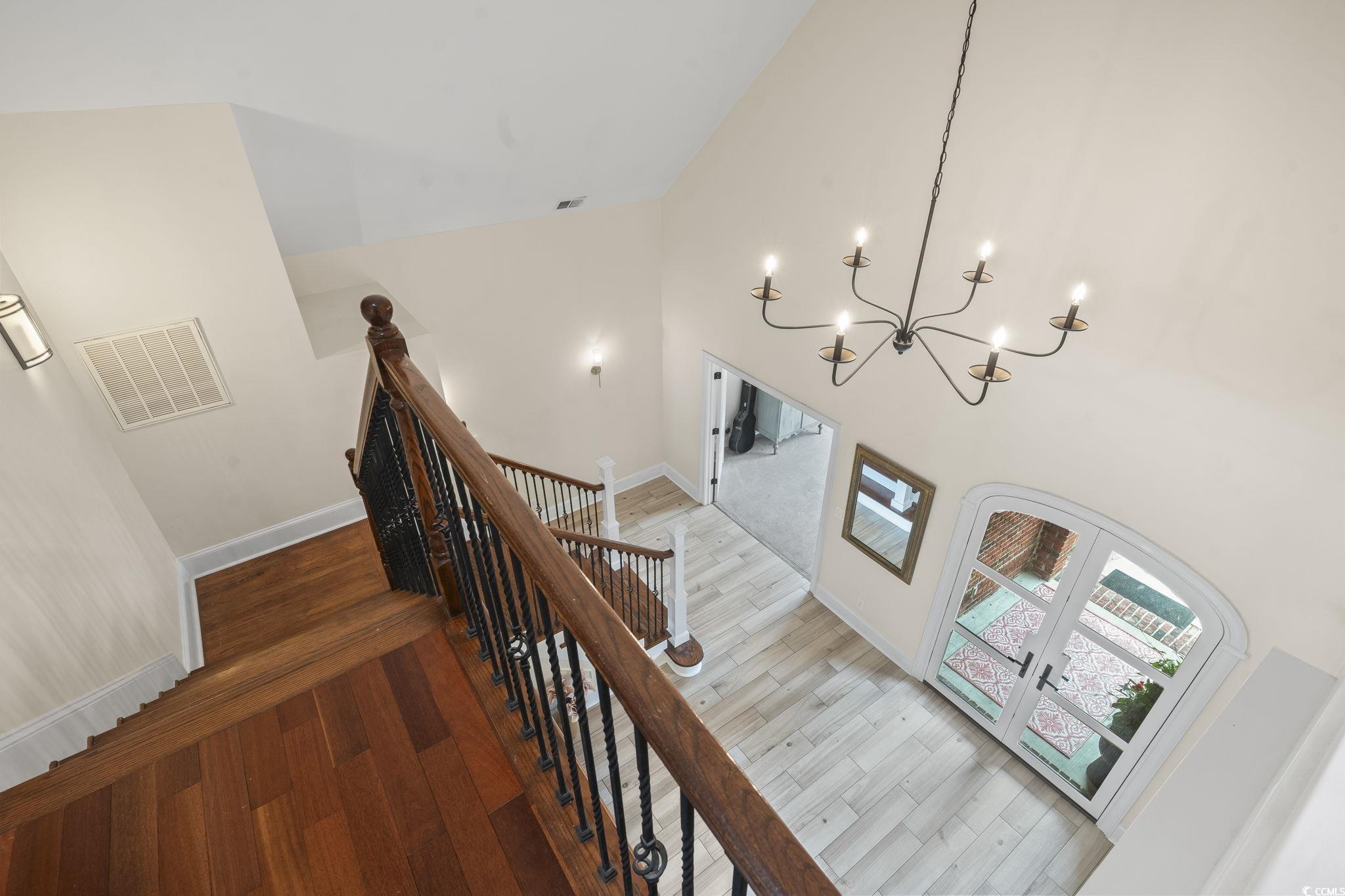 9449 Freewoods Road Myrtle Beach, SC 29588 - Photo 31 of 39 Staircase featuring a chandelier, french doors, wood finished floors, baseboards, and high vaulted ceiling
