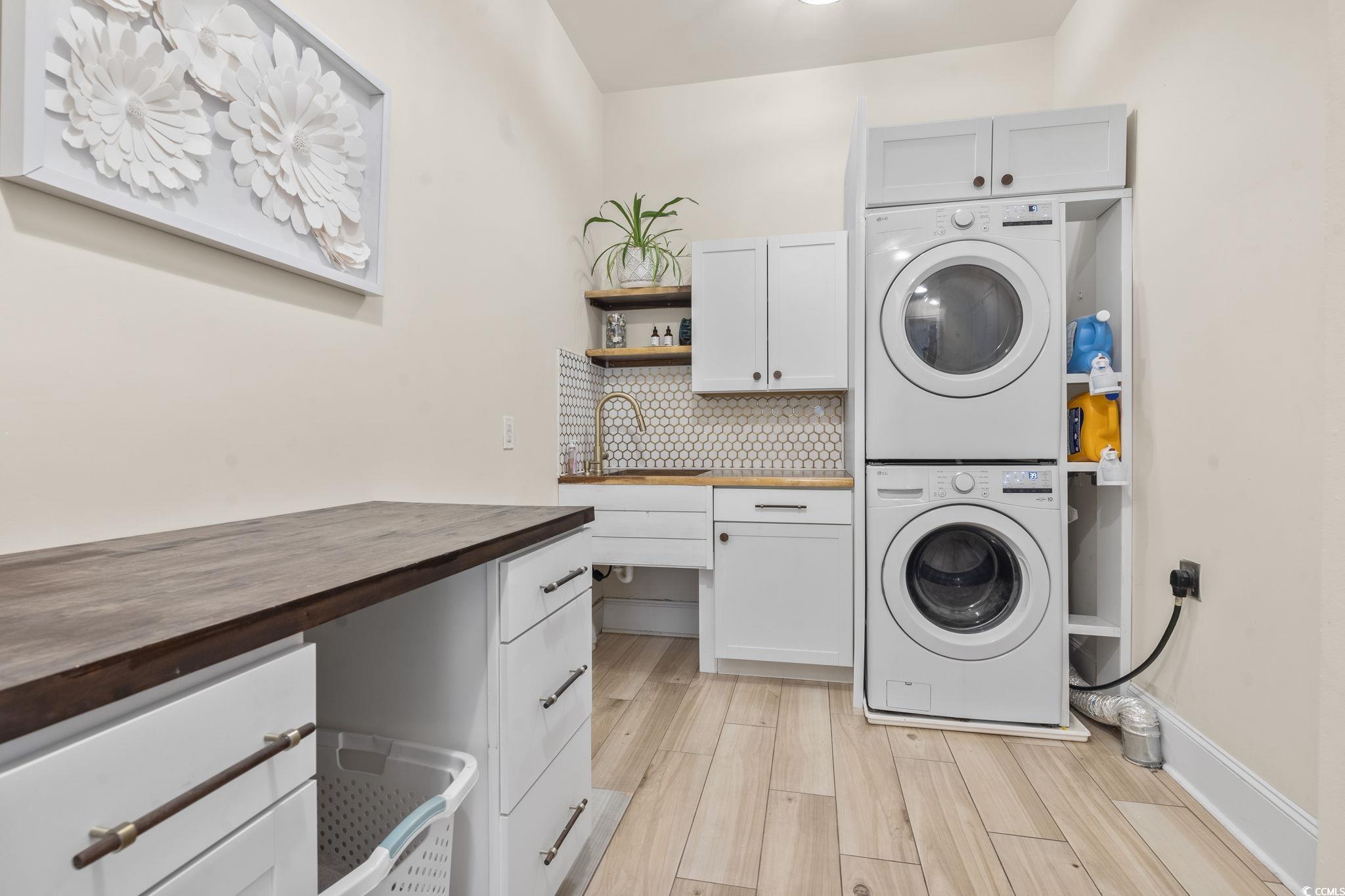 9449 Freewoods Road Myrtle Beach, SC 29588 - Photo 32 of 39 Laundry room featuring cabinet space, stacked washer / drying machine, and light wood-style floors