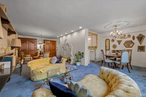 a living room with furniture kitchen view and a chandelier