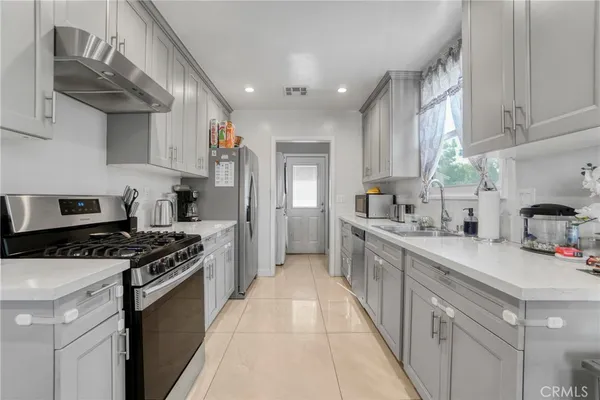 a kitchen with stainless steel appliances a sink dishwasher stove and refrigerator