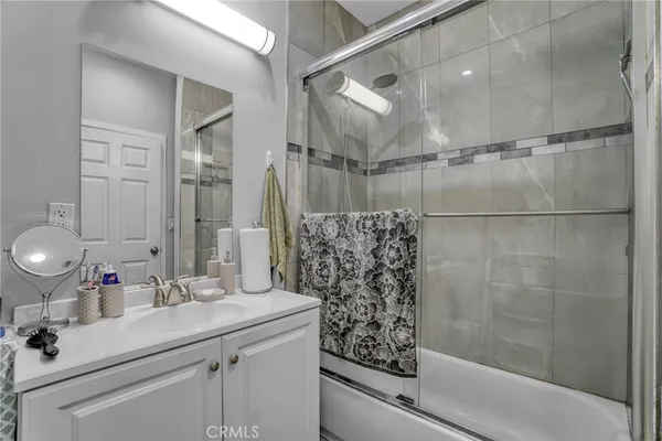 a bathroom with a sink vanity granite tub shower and a mirror