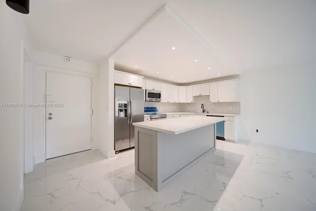 a large white kitchen with a stove top oven a refrigerator and white cabinets