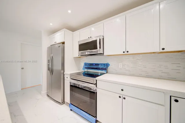 a kitchen with white cabinets and stainless steel appliances