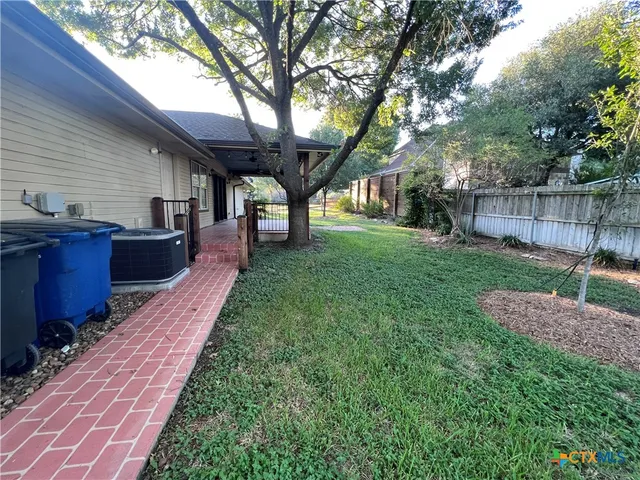 a backyard of a house with wooden fence and large trees