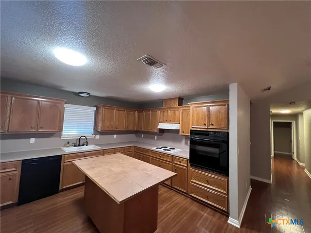a kitchen with stainless steel appliances kitchen island granite countertop a stove a sink and a refrigerator