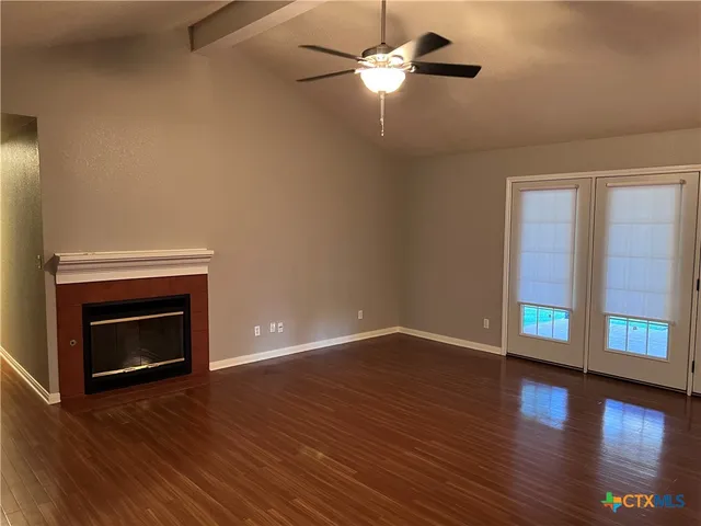 a view of an empty room with wooden floor fireplace and a window