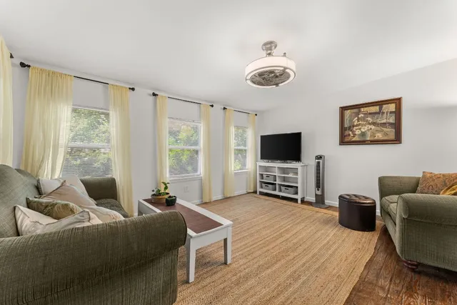 a living room with furniture a flat screen tv and a large window