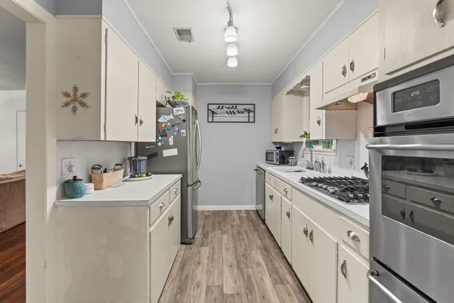 a kitchen with stainless steel appliances white cabinets sink and stove