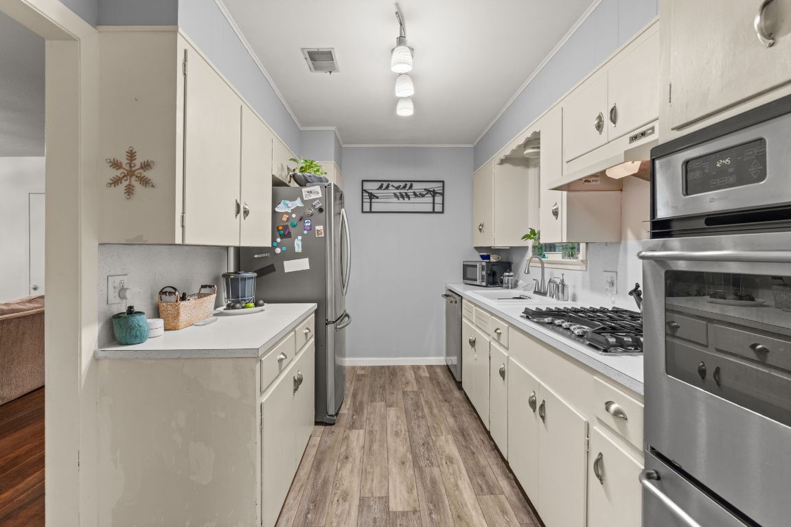 1303 Alegria Road Austin, TX 78757 - Photo 8 of 25 a kitchen with stainless steel appliances white cabinets sink and stove