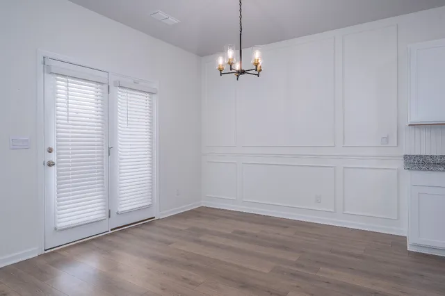 an empty room with wooden floor cabinet and windows