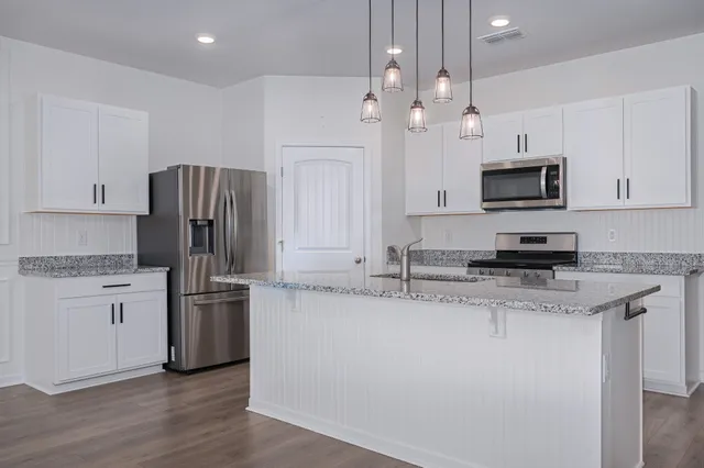 a kitchen with stainless steel appliances granite countertop a refrigerator a stove a sink and a granite counter tops