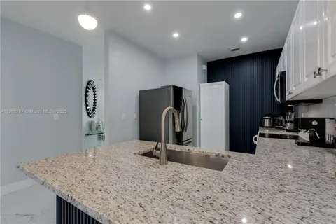 a kitchen with stainless steel appliances granite countertop a sink a refrigerator and a granite counter tops