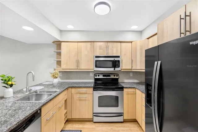 a kitchen with granite countertop a sink stainless steel appliances and white cabinets