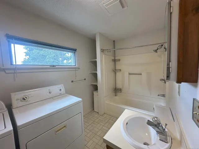 a bathroom with a sink a bathtub and a window
