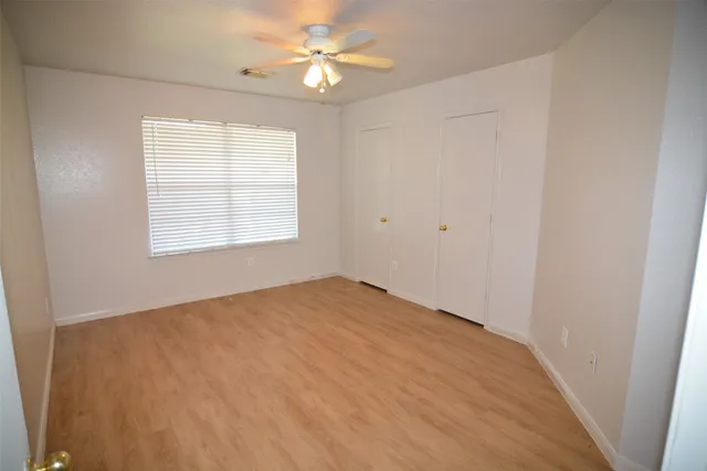 an empty room with windows and fan
