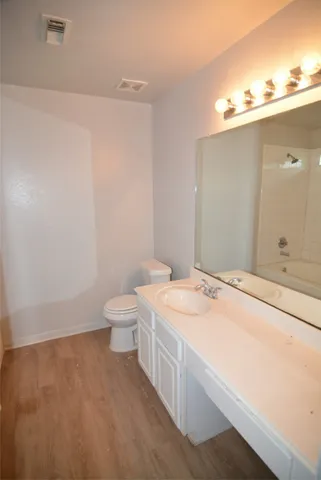 a spacious bathroom with a granite countertop sink a toilet and a mirror