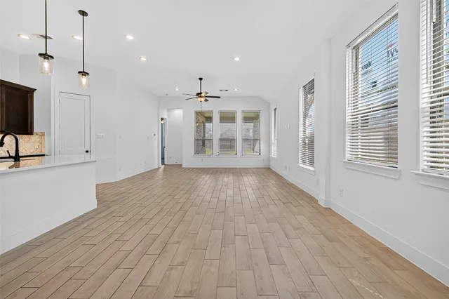 a view of an empty room with a window and wooden floor