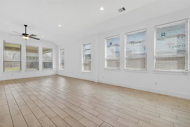 a view of an empty room with a window and wooden floor