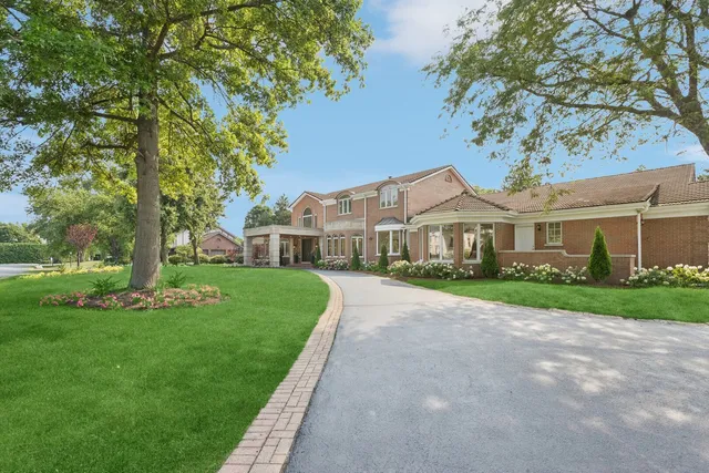 a front view of a house with a garden and trees