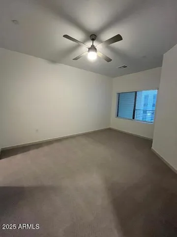 an empty room with a chandelier fan and windows