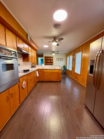 a kitchen with stainless steel appliances granite countertop wooden floors a stove and a sink