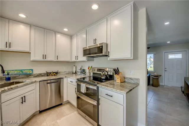 a kitchen with granite countertop white cabinets sink and stainless steel appliances