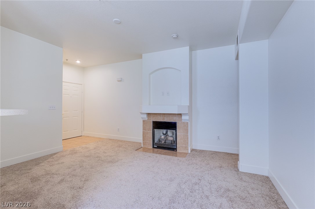 9050 West Warm Springs Road, Unit 1011 Las Vegas, NV 89148 - Photo 2 of 32 A cozy living space features a tiled fireplace, providing a focal point for relaxation and comfort.