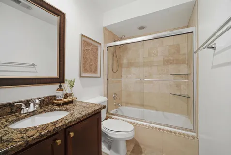 a bathroom with a granite countertop sink toilet and shower