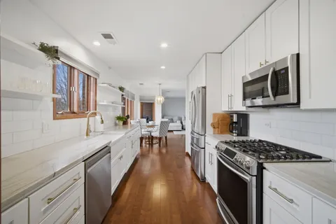 a large kitchen with stainless steel appliances granite countertop a lot of counter space a sink and dishwasher a stove top oven with wooden floor