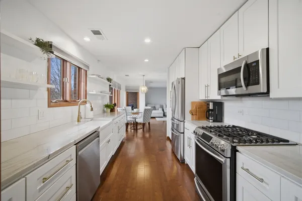 a large kitchen with stainless steel appliances granite countertop a lot of counter space a sink and dishwasher a stove top oven with wooden floor