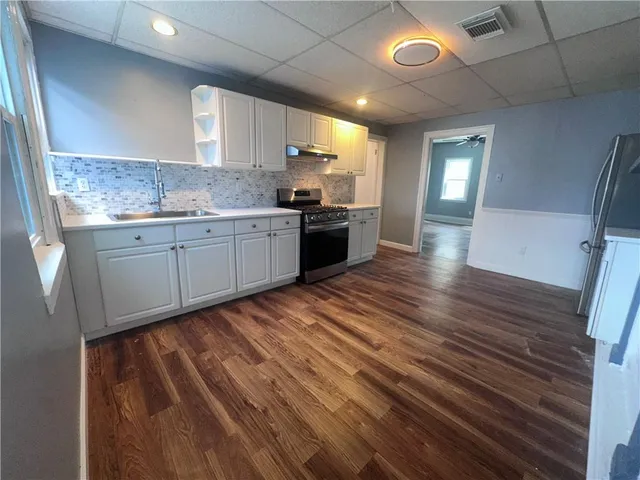 a kitchen with granite countertop wooden floors a sink and appliances