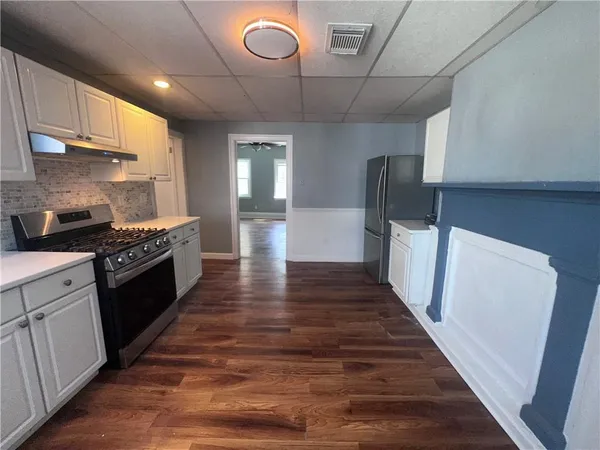 a large kitchen with stainless steel appliances wooden floors and a view of living room